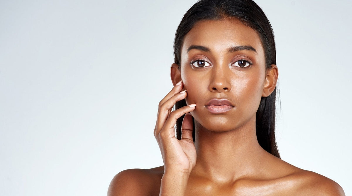 Portrait of a woman touching her face to illustrate sensitive, reactive skin 