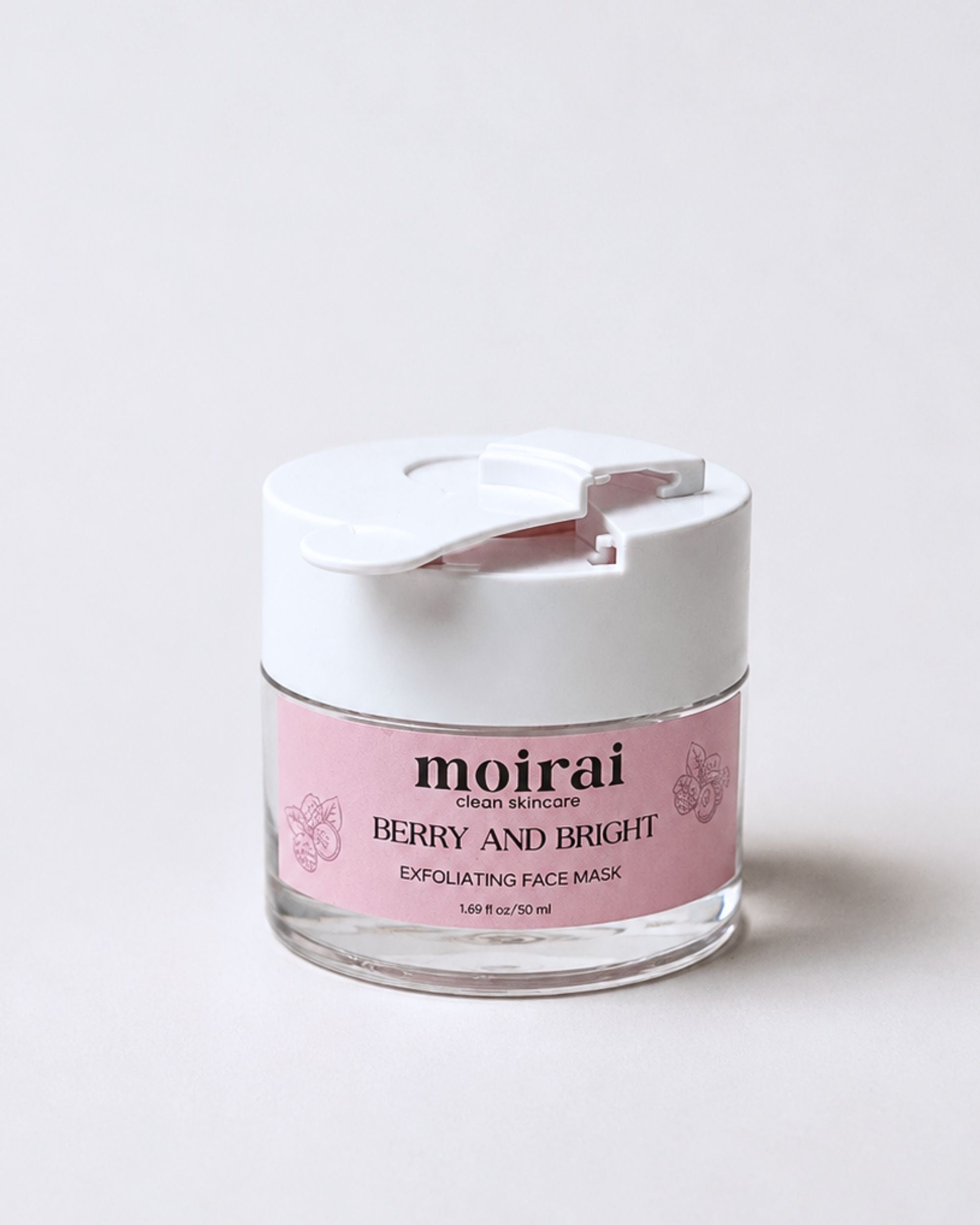 A clear plastic jar of Moirai Skincare Berry and Bright Face Mask with a pink label and a white top lid with a mask spoon, set against a plain light gray background.