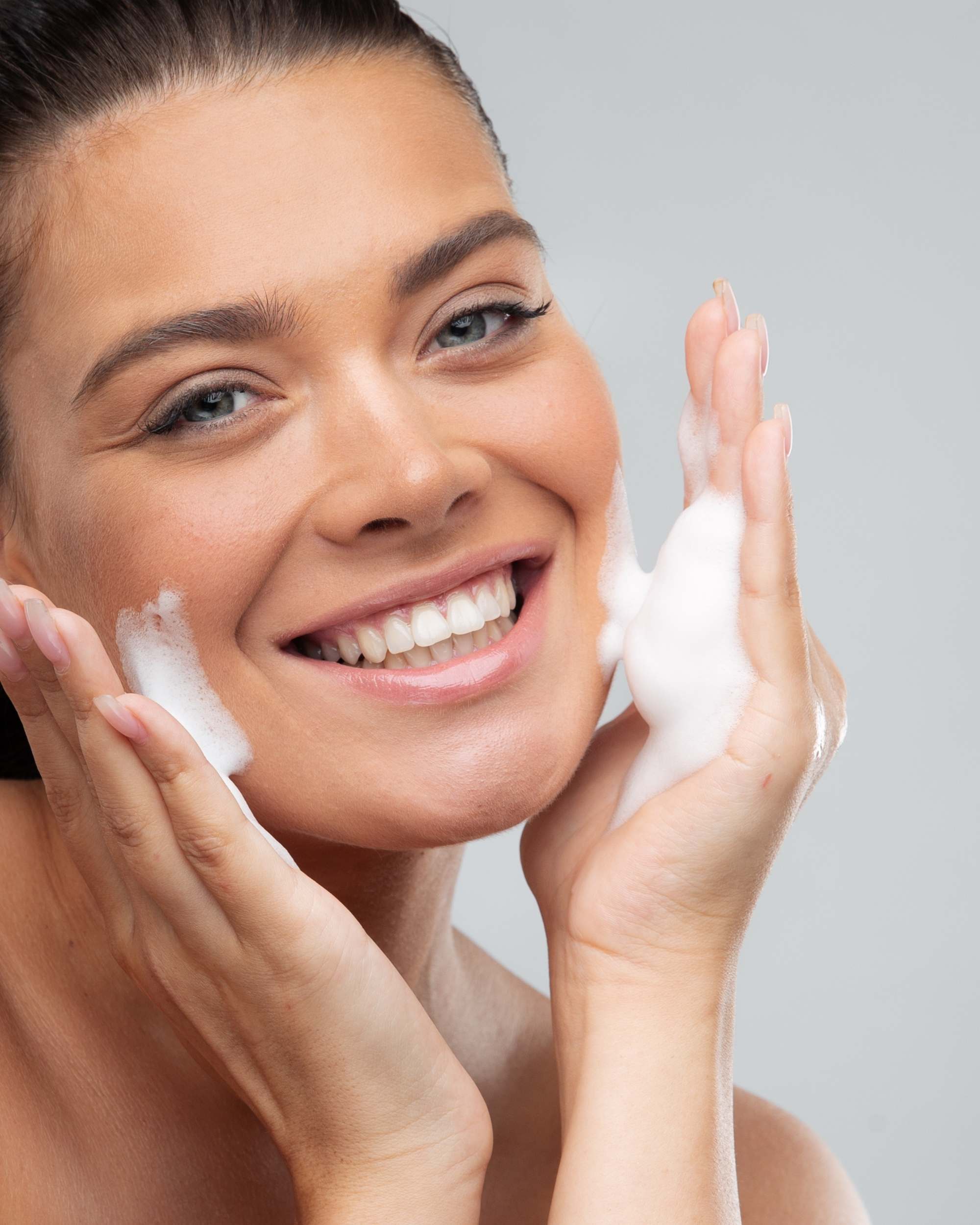 Woman washing face with Moirai Blue Tansy & Matcha Gel Cleanser