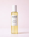 Moirai Citrus C Brightening Toner with Vitamin C in a clear yellow bottle on a soft blush background