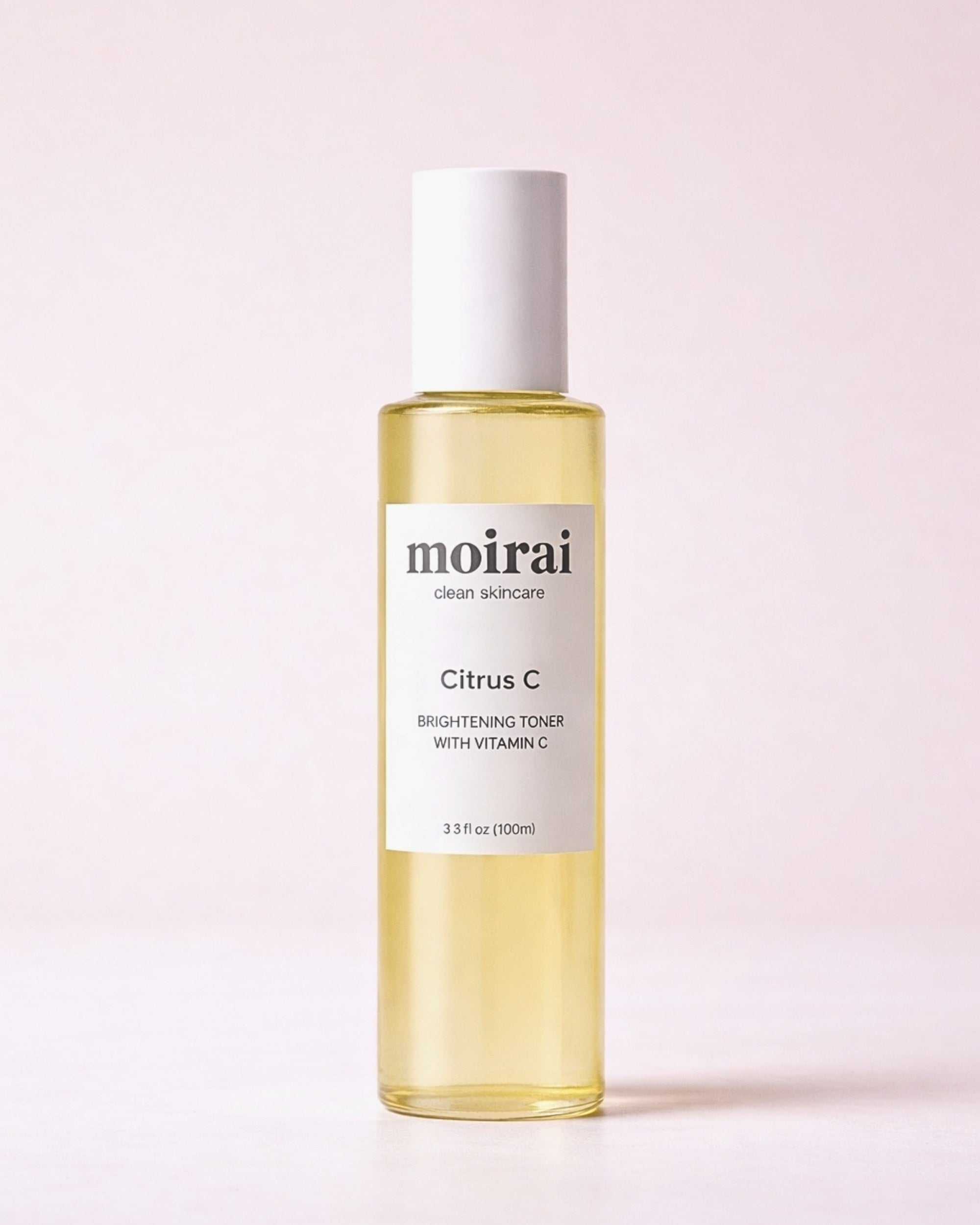 Moirai Citrus C Brightening Toner with Vitamin C in a clear yellow bottle on a soft blush background