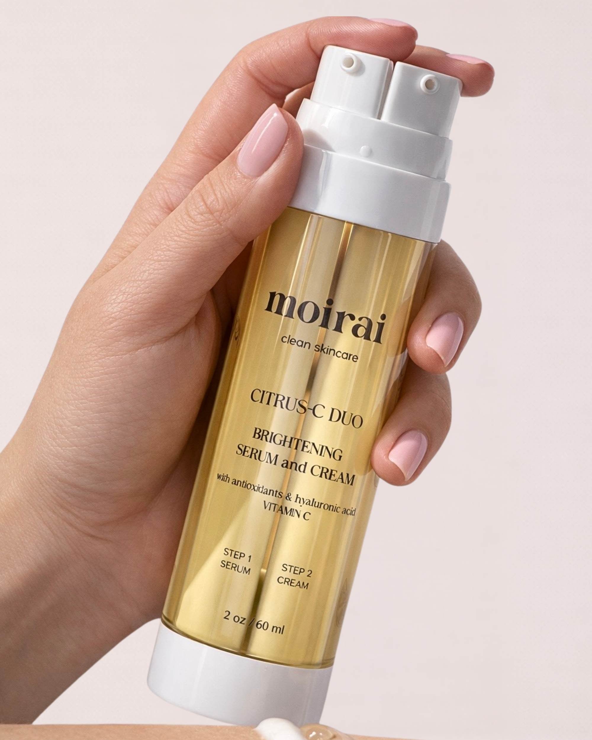 Hand holding Moirai Citrus-C dual- chamber bottle with brightening vitamin C serum and cream for radiant skin