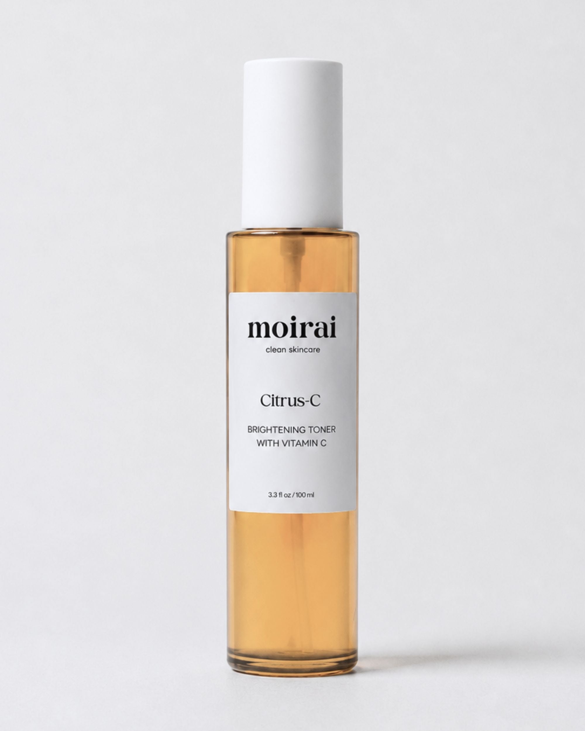 A bottle of Moirai Citrus-C Brightening Toner with Vitamin C, featuring amber-colored liquid inside a clear glass bottle with a white cap and white label, set against a light gray background.