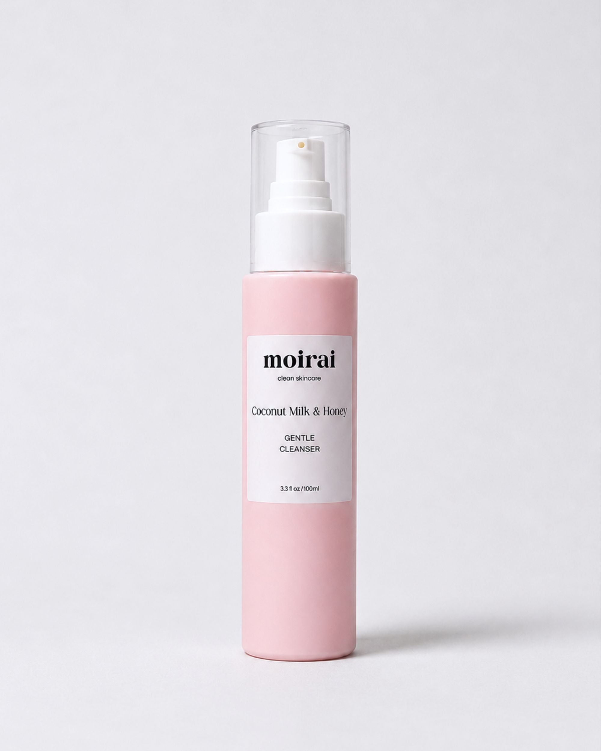 A bottle of Moirai Gentle Cleanser with Coconut Milk & Honey for sensitive skin, featuring a light pink bottle, white pump dispenser, and clear cap, set against a clean light gray background