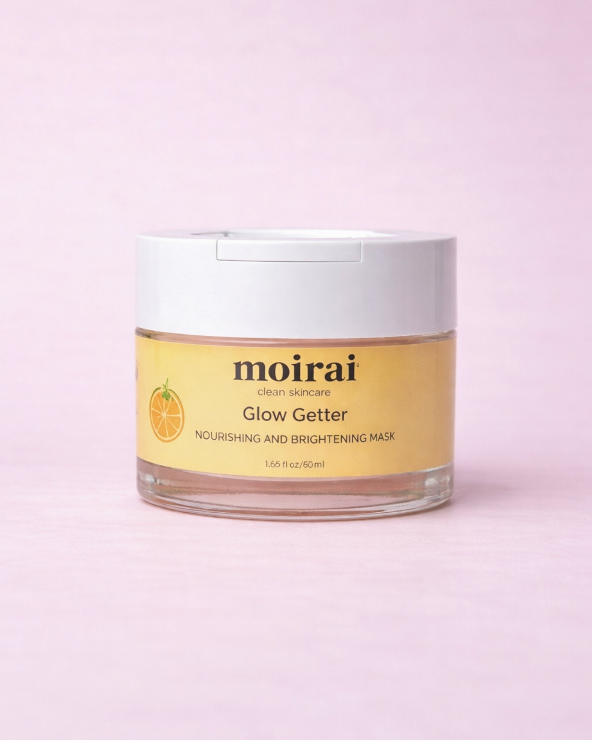 Moirai Glow Getter Nourishing and Brightening Moirai Glow Getter Nourishing and Brightening Mask in a clear jar with white lid on a soft blush pink background.