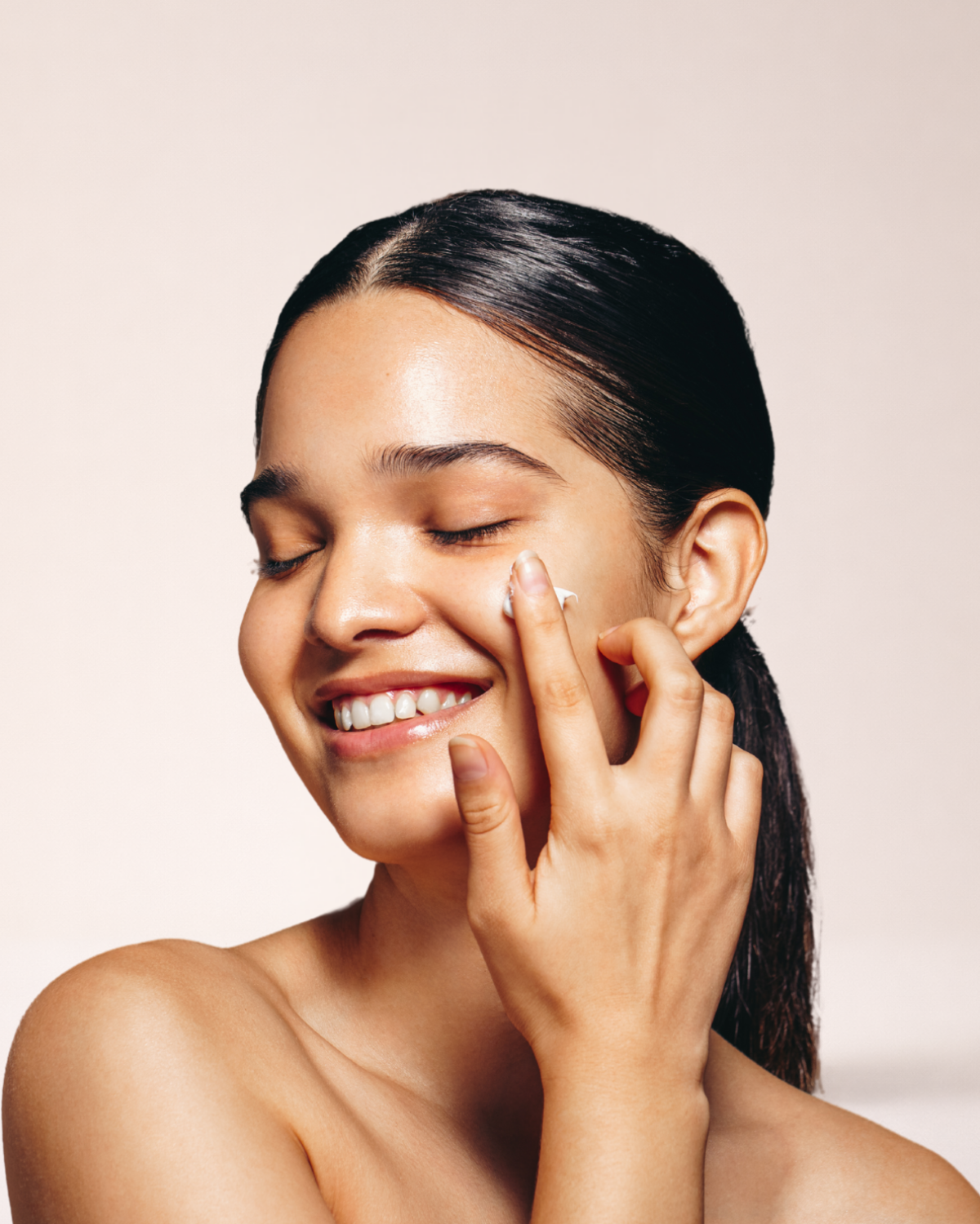 Woman applying moirai calm and repair duo cream to her face with a neutral background