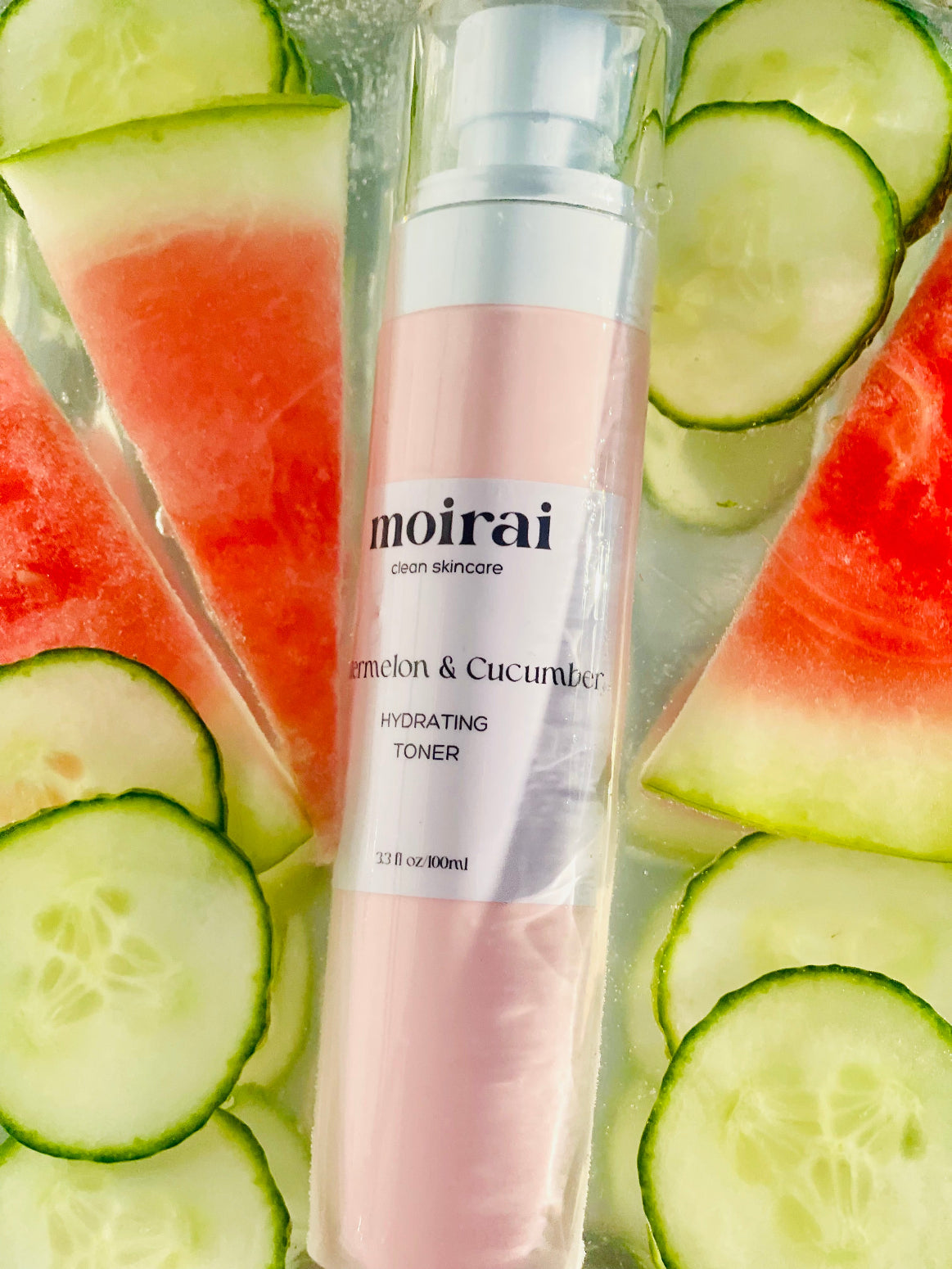 Moirai Watermelon & Cucumber Hydrating Toner bottle styled with cucumber slices and watermelon wedges in water.